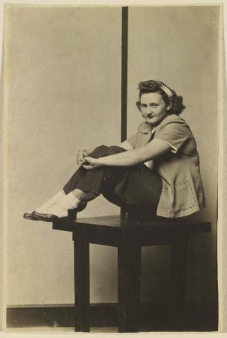 [Woman siting on table, knees bent, saddle shoes]