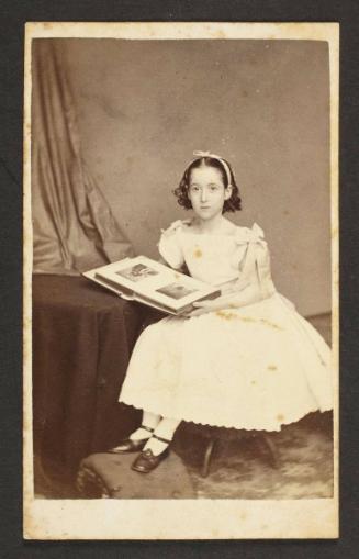 Unknown sitter [Portrait of a seated girl posed with a cabinet card album]
