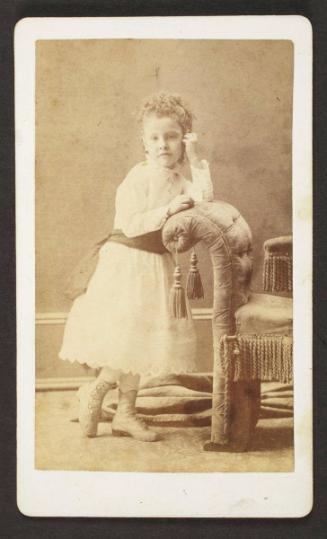 Unknown sitter [portrait of a girl standing next to upholstered bench]
