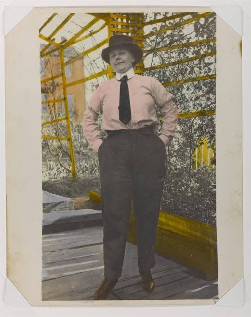 [Woman in pink shirt, tie and trousers]