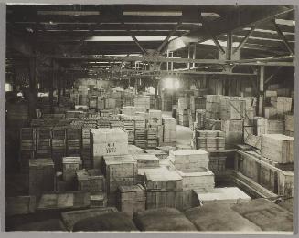 [Warehouse filled with stacks of crates]