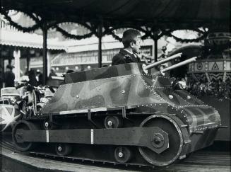Military aeroplanes merry-go-round. Germany has novelty merry-go-rounds. Instead of black and white horses, motorbikes etc., young and old enjoy riding in tanks. This new merry-go-round is shown at Berlin's Christmas Fair.
