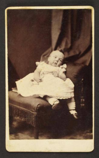 Unknown sitter [portrait of infant on upholstered armchair]