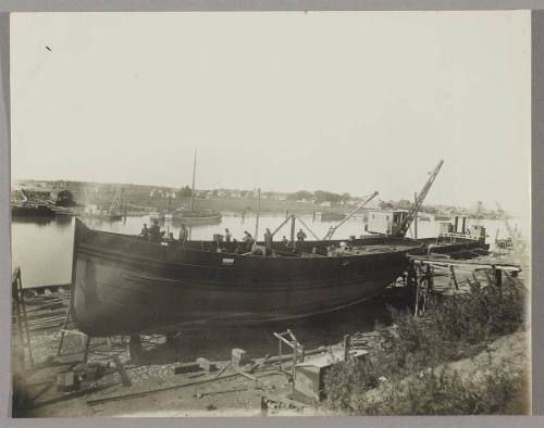 Tug under construction at the Pontbriand Ltée, Sorel, QC [Completed boat hull with workers continuing construction on deck]