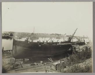 Tug under construction at the Pontbriand Ltée, Sorel, QC [Completed boat hull with workers continuing construction on deck]