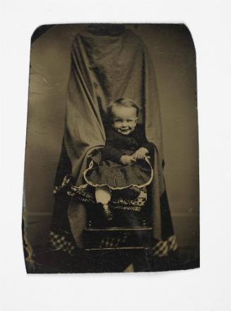 Portrait of young child (seated in front of shrouded figure)