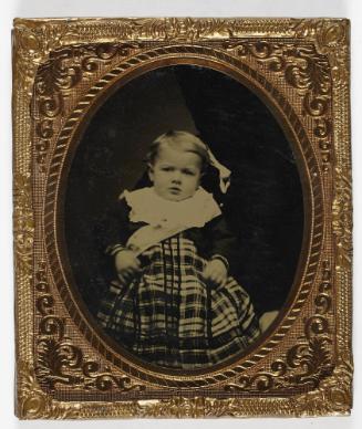 Portrait of young boy in plaid dress (seated on lap of defaced figure)