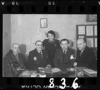 A Jewish policeman and members of the ghetto administration at a desk