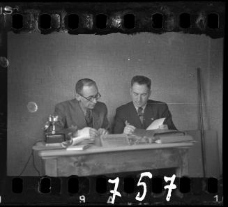 Transport Department administrator, Mr. Elefant (left), working at desk with member of the ghetto administration