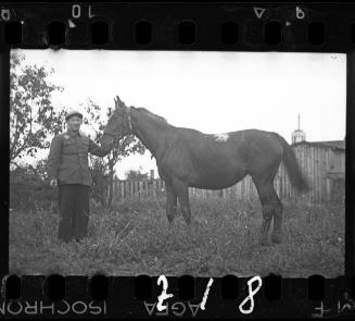 Man posing with a horse in a yard in the ghetto