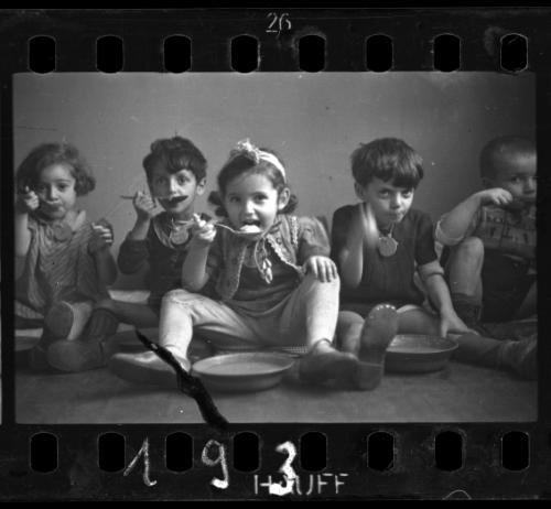 Five children sitting on floor and eating