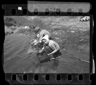 Children in pond searching for items to salvage
