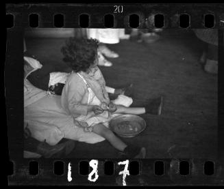 Little girl sitting on floor mat with food tray