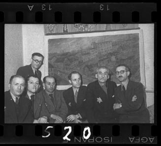 Members of the Judenrat sitting in front of a painting