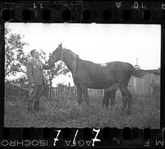 Dr. Kagan, hospital administrator, posing with a horse in a yard