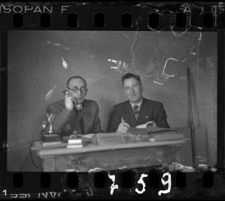 Transport Department administrator, Mr. Elefant (left), talking on the phone beside member of the ghetto administration