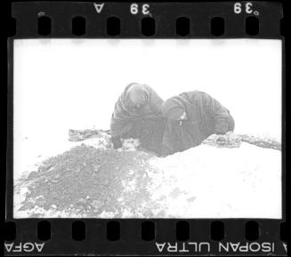 Two residents digging in the ground in winter