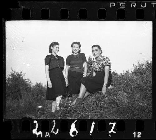 Three women seated on a hill