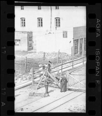Two Jewish policemen beside an entry gate to the ghetto