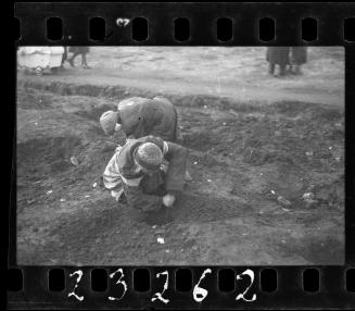 Two women searching the ground for food, coal and other provisions