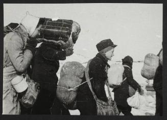 Boy in cap, with satchel and sack tied to back, walking with winter deportation crowd -side-profile