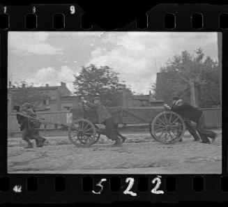 Boys pushing cart, probably a hearse
