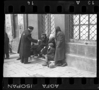 Street scene with residents sitting on the doorsteps of a building