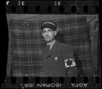Portrait of a Jewish policeman standing in front of a plaid blanket