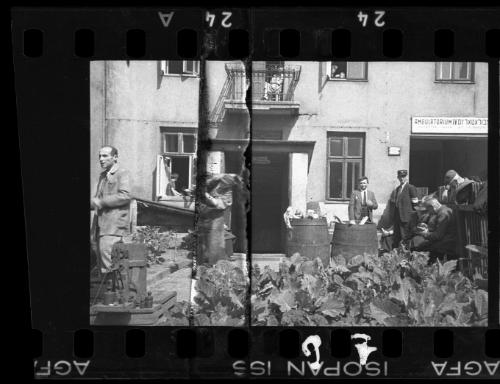 Group of men with barrels of foodstuff outside a hospital in the ghetto