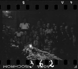 Children and parents gathered around the table at a children's party