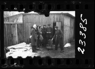Group of residents gathered outside a wooden shed in winter