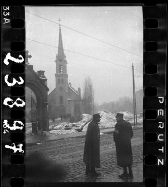 Two Jewish policemen standing in street outside a church in winter