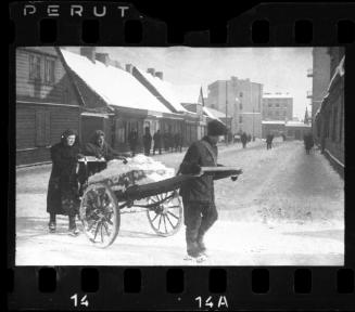 Three people moving cart with snow