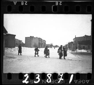 Residents walking in the street with their belongings during a deportation in winter