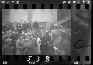 Man making an announcement to a large group of residents in the street