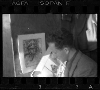 Mendel Grossman holding a portrait of a German administrator, beside a portrait of a German officer