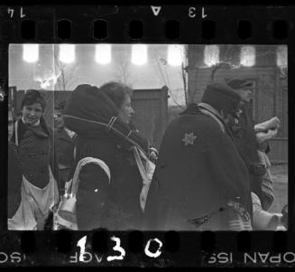 Woman carrying blanket-wrapped parcel around her shoulders, awaiting deportation