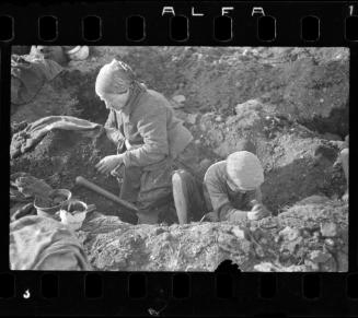 Elderly woman and young boy digging a pit in search of provisions