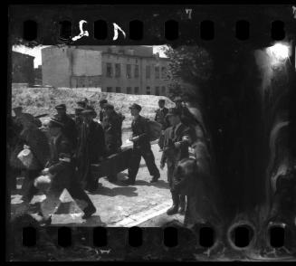 Residents and policemen walking with belongings during deportation from the Lodz Ghetto