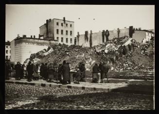 Small group of residents standing on street next to the ruins of the synagogue on Wolborska Street, destroyed by the Germans in 1939