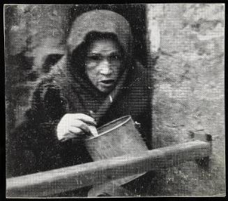 Starved old woman eating from a pail