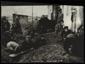 Man digging pit while boys search the ground for potatoes