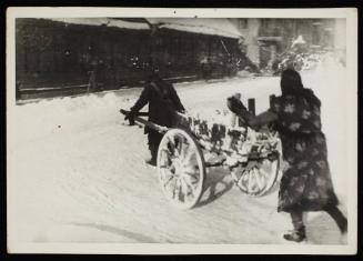 Two people moving cart with snow