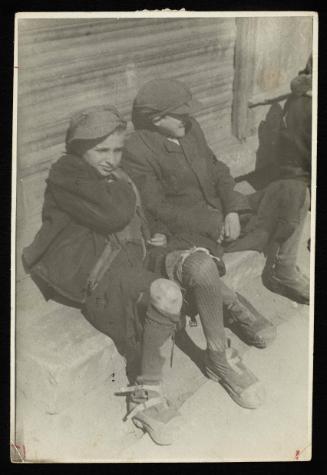 Two boys sitting on street