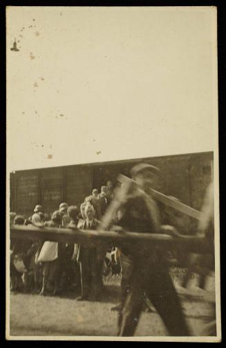 Residents boarding deportation train at Radogoszcz Station, man with lumber in the foreground
