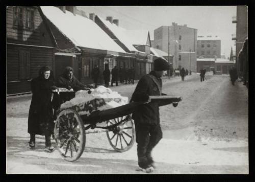Three people moving cart with snow