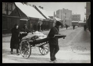 Three people moving cart with snow