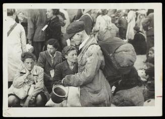 Old man carrying pail with sack on back, in deportation crowd