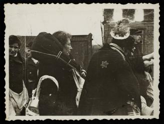 Woman carrying blanket-wrapped parcel around her shoulders, awaiting deportation