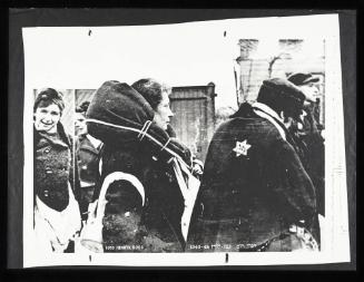 Woman carrying blanket-wrapped parcel around her shoulders, awaiting deportation